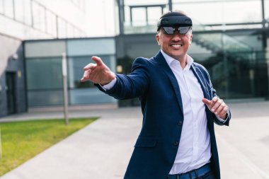 İş kıyafetli bir adam dışarıdaki bir sanal gerçeklik arayüzünde gezinmek için jestler kullanır..