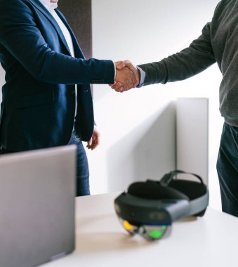 A close-up view of a handshake between a businessman and a client, symbolizing the successful deal for VR glasses in an office. clipart