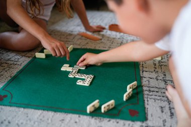 Domino oynayan bir grup insan var. Oyunculardan biri tahtadaki bir taşı işaret ediyor.