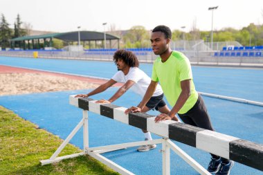 İki Afrikalı bir adam bir pistte geriniyor. Biri yeşil gömlek giyiyor.