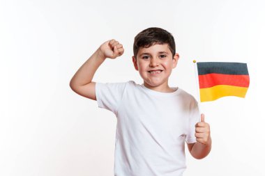 Beyaz gömlekli bir çocuk coşkuyla yumruğunu kaldırıyor ve elinde bir Alman bayrağı tutuyor..