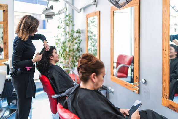 A hairdresser combs a client's hair in a modern salon, ensuring a stylish look. Concept of professional hair styling and client comfort.