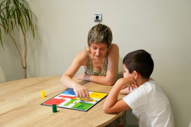 A mother and son share a joyful moment, smiling and playing a board game together. Concept of family happiness and bonding through play. clipart