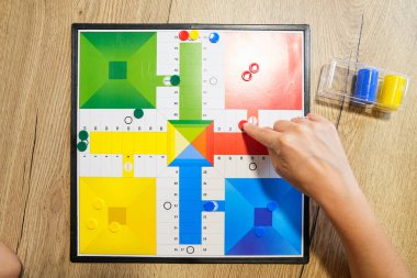 Renkli bir masa oyununun yakın plan çekimi. Anne eli bir parçayı hareket ettiriyor, strateji ve oyun oynuyor. Stratejik düşünme ve etkileşimli eğlence kavramı.