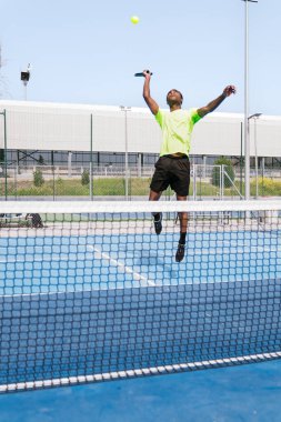 Afrika kökenli bir sporcu, dışarıda oynanan bir futbol maçında güçle hizmet etmeye hazırlanıyor. Sporda odaklanma ve güç kavramı.