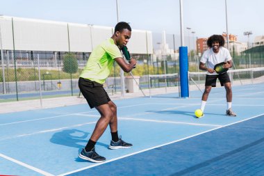 Bir Afrikalı oyuncu topa vurmaya hazırlanırken takım arkadaşı her ikisi de oyuna dahil olur. Hazırlık kavramı, Afrika etnik kökeni ve odaklanma.