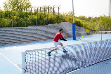 Bir oyuncu kaleye yakın bir atış yapmaya hazırlanıyor. Pickleball maçında. Beklenti ve hassasiyet kavramı.