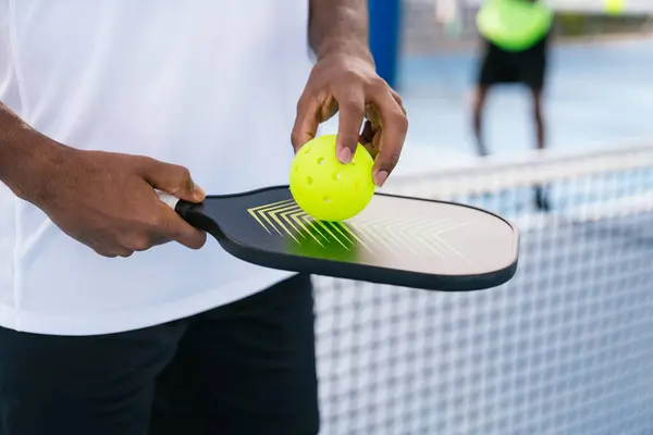 Yankesicinin yakın çekimi ve topu Afrikalı bir Amerikalı oyuncu tutuyor. Maç için hazır. Pickleball 'da ekipman ve hazırlık kavramı.