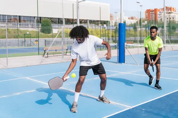 Afrikalı oyuncular, çiftler halinde yapılan bir picleball maçında koordinasyon ve strateji anlarını paylaşıyorlar. Takım çalışması kavramı, Afrika etnik kökeni ve keyfi.