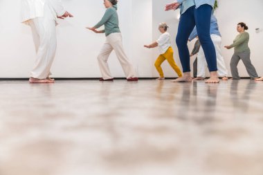 Bir grup yaşlı kadın, eğitmenlerinin rehberliğinde yoga yapıyor. Yaşlılar için grup sağlığı, farkındalık ve fiziksel sağlık kavramı.