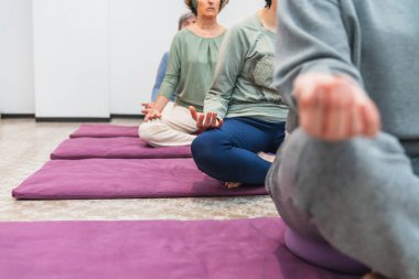 Meditasyon poziyonunda son sınıf kadınlarının yoga dersinde farkındalık yaptığını gösteren yakın çekim. İç huzur, odaklanma ve rahatlama kavramı.