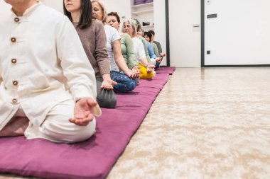 Bir yoga eğitmeni, yaşlı kadınlara, farkındalık ve sakinliğe odaklanmış bir meditasyon oturumunda önderlik eder. Ruhani denge, rahatlama ve grup çalışması kavramı.