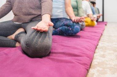 Son sınıf kadınlarının yakın çekimi ve bir yoga eğitmeninin farkındalık oturumu sırasında oturarak meditasyon yapması. Odaklanma, rahatlama ve grup meditasyonu kavramı.