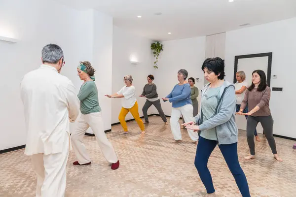 Bir grup son sınıf öğrencisi, yoga pozları veriyor. Eğitmenlerinin rehberliğinde dikkatle bakıyorlar. Yaşlılar için odaklanma ve denge kavramı.