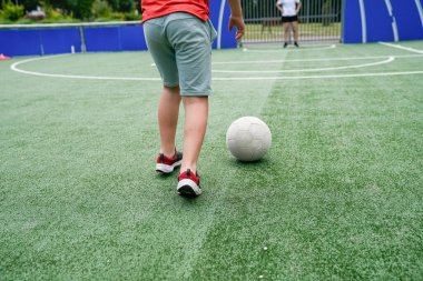 Çocuk, annesi bloklamaya hazırlanırken topa vurmaya hazırlanıyor. Spor yoluyla aile eğlencesi ve beceri geliştirme kavramı.