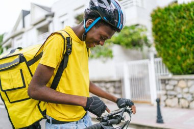 Genç Afrikalı bisikletçi sakin bir banliyö mahallesinde GPS 'ini kontrol ediyor. Modern yemek teslimatı kavramı.