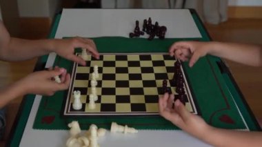 İki çocuk satranç oynuyor. Çocuklardan biri beyaz bir gömlek giyiyor. Diğer çocuk beyaz gömlek ve şort giyiyor.