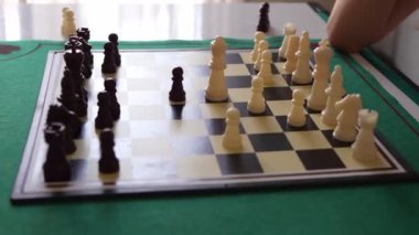 İki çocuk satranç oynuyor. Çocuklardan biri beyaz bir gömlek giyiyor. Diğer çocuk beyaz gömlek ve şort giyiyor.