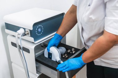 Mavi lateks eldiven giyen bir güzellik uzmanı estetik kliniğinde vücut şekillendirme tedavisi için profesyonel ekipman hazırlıyor.