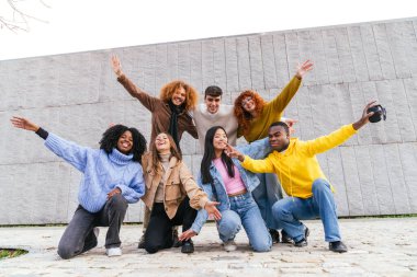 Bir grup çok ırklı arkadaş birlikte eğleniyor ve şehirde fotoğraf çekiyorlar.