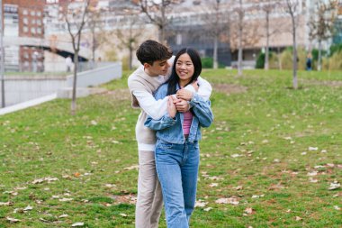 Genç, etnik çeşitlilikte bir çift parkta kucaklaşıyor, romantik bir anın tadını çıkarıyorlar.