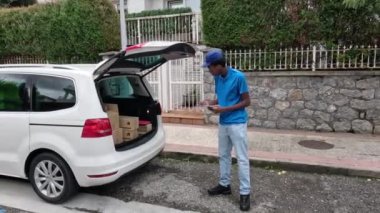 Arabasında paketler düzenleyen, teslimatlara hazırlanan bir kurye. Lojistik ve verimli paket hizmeti kavramı.