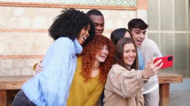 Çeşitli arkadaş grupları dışarıda mutlu bir selfie çekiyorlar. Neşeli ifadeler ve günlük kıyafetlerle..