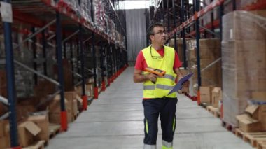 Depo çalışanı, geniş bir depoda envanter kontrolü yapmak için tarayıcı kullanıyor.