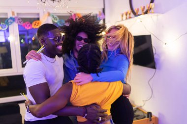 Dört neşeli çoklu etnik arkadaş canlı bir ev partisinin keyfini çıkarıyorlar. Canlı bir enerjiyle kucaklaşıp dans ediyorlar.