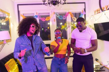 Çok ırklı arkadaşlar neşeli bir ev partisinde neşe içinde şarkı söyleyip dans ediyorlar. Kahkaha ve eğlenceyle dolu unutulmaz anlar yaratıyorlar.