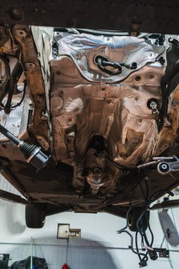 Profesyonel bir oto tamir atölyesinde arabanın şasisinin düşük açılı görüntüsü.