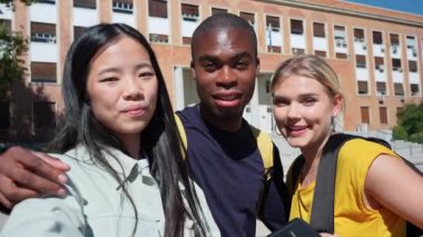 Çok ırklı üniversite öğrencileri kampüste yavaş çekimde selfie çekerek neşeli bir anı yakalıyorlar.