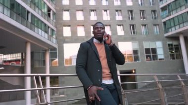 Başarılı bir iş adamı modern bir ofis binasının dışında hoş bir telefon görüşmesi yapıyor.