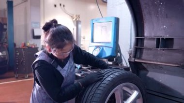 Tekerlek dengeleme makinesini çalıştıran yetenekli bir tamirci, hassas lastik dengesi ve ideal araç performansı sağlıyor