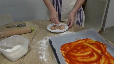 Anne ve çocuk, ton balığıyla ev yapımı pizza hazırlarken ahşap mutfak masasında yemek pişirme anlarını paylaşıyorlar.