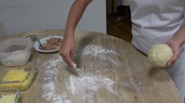 Beyaz önlük giyerken pizza hamuru yoğuran genç şef, ev mutfağında aile yemeği yaparken un ahşap yüzey üzerinde aşçılık becerileri öğreniyor.