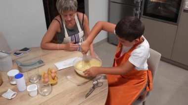Yemek pişirme becerileri, ilgili anne, sıcak aile mutfağında birlikte ev yapımı sünger keki hazırlarken küçük oğluna un tarlasında rehberlik ediyor.