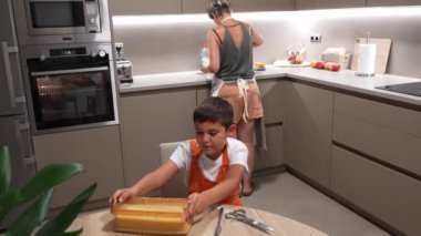 Yemek pişirme becerileri, ilgili anne, sıcak aile mutfağında birlikte ev yapımı sünger keki hazırlarken küçük oğluna un tarlasında rehberlik ediyor.