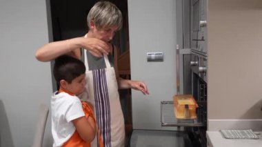 Yemek pişirme becerileri, ilgili anne, sıcak aile mutfağında birlikte ev yapımı sünger keki hazırlarken küçük oğluna un tarlasında rehberlik ediyor.