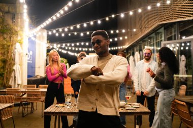 Çoklu etnik arkadaşlardan oluşan bir grup, gece eğleniyor, dans ediyor ve festival ışıkları altında sosyalleşiyorlar.