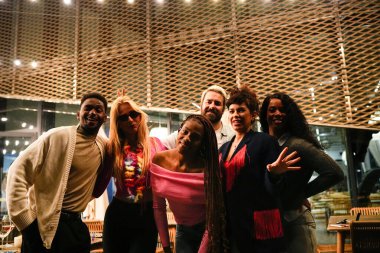 Bir grup neşeli çoklu etnik arkadaş birlikte eğleniyor, poz veriyor ve gülümsüyor.