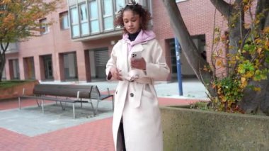 Açık havada akıllı telefon kullanan, konuşan, mesajlaşan ve selfie çeken zarif genç bir kadın yavaş çekim montajında.