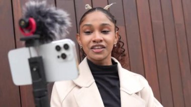 Genç bayan muhabir akıllı telefon ve harici mikrofon kullanarak video blogu kaydediyor.