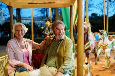 Yaşlı çift lunaparkta atlıkarıncaya binip emekliliklerinin tadını çıkarıyorlar.