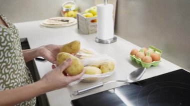 Kaliteli ev yapımı patatesleri paslanmaz çelik tencerede kaynatma, endüksiyon ocağında pişirme, açık mutfak ortamında kusursuz mutfak hazırlığı.