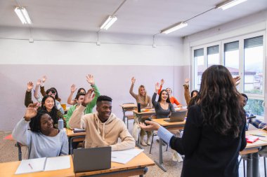 Çok ırklı öğrenciler, öğretmenlerinin sorularını cevaplamak için aktif olarak el kaldırıyorlar.