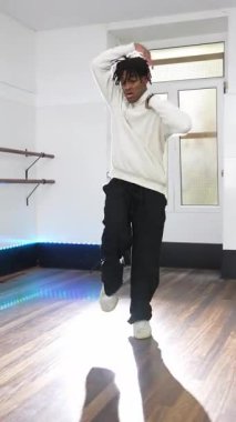 Profesyonel hip hop dansçısı dinamik, yüksek enerjili hareketler sergiliyor. Parlak, ferah stüdyoda, akışkan vücut hareketleri yoluyla teknik beceri ve sanatsal ifade sergiliyor.