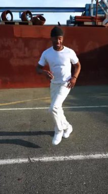 Endüstriyel duvar kenarında dinamik hip hop koreografisi yapan yetenekli genç dansçı sokak dansı enerjisini ve sanatsal hareketi ifade ediyor.