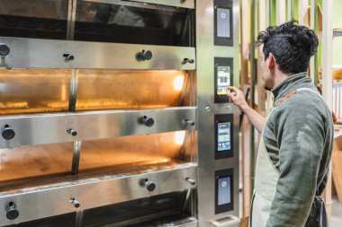 Fırıncı fırının modern dijital panelinde ısıyı ayarlıyor, fırında veya pastanede çalışıyor