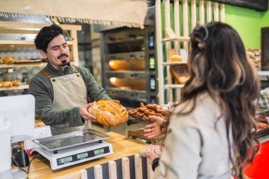 Fırında yeni pişmiş ekmekle müşteriye servis yapan fırıncı mükemmel müşteri hizmetleri sunuyor.